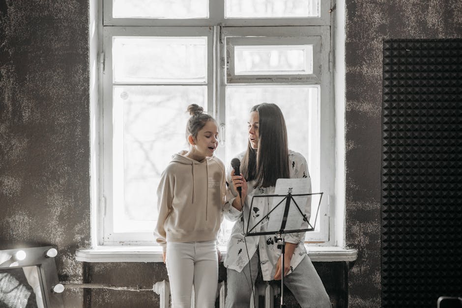 A young girl and her teacher practicing singing in a music studio.